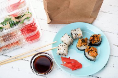 Suşi yuvarlama setli plastik kutular, rulo rulo ve kese kağıdıyla tabak. Yemek teslimatı