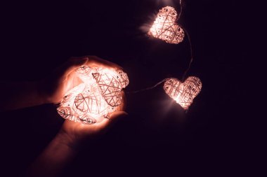 Ellerinde parlayan kalp şeklinde güzel peri ışıkları. Sevgililer Günü