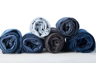Beyaz arkaplanda farklı sarılmış kot pantolon yığını