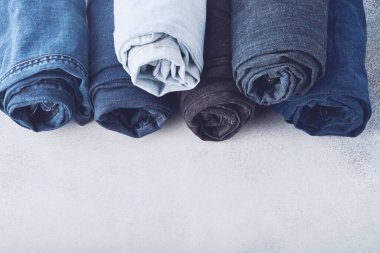 Beyaz arkaplanda farklı sarılmış kot pantolon yığını