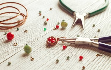 Renkli boncuklar, bakır tel ve mücevher aletleri. Kablo sarma