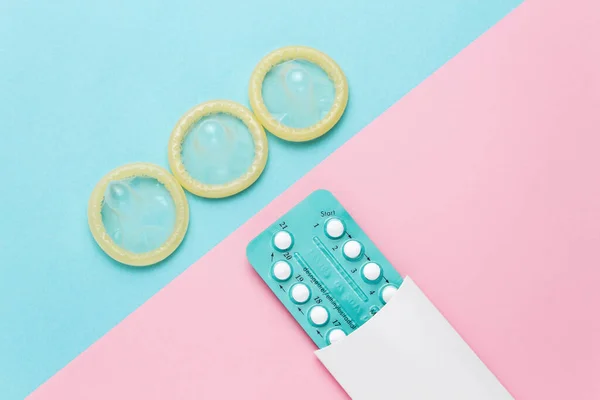避妊薬と色の背景にコンドーム 上からの眺め 避妊の概念 — ストック写真