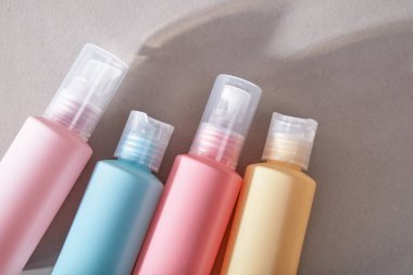 Seyahat çantası. Kozmetik ürünleri için dört plastik şişe. Gölgeli gri arkaplan.