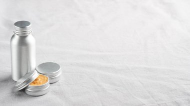 Keten kumaş üzerinde doğal kozmetik ürünler içeren metal kaplar.