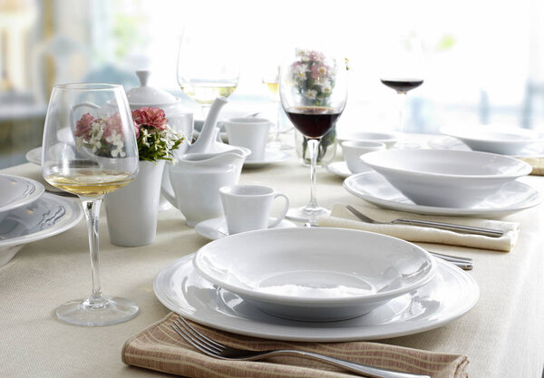 Served restaurant table with white dishes, cutlery and wineglasses 