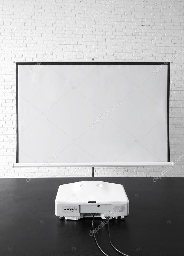 Screen for projector placed close to white brick wall
