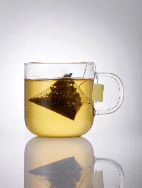 Closeup of glass tea cup with tea packet on grey background