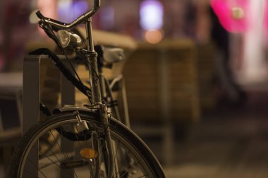 Eski bir fahioned Bisiklet arka planda renkli ışıkları ile gece bir sokak Bank için kilitli.