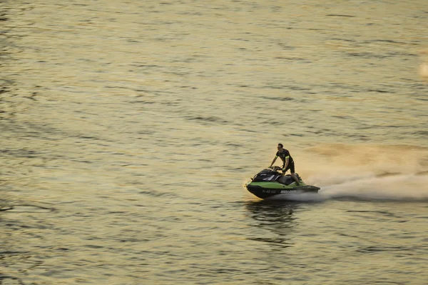 A person riding a jetski at speed on calm water.