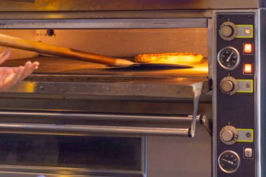 Fırından taze fırında pizza toplamak için pizza küreği kullanıyor.