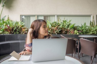 Kadının dikkati açık kahve dükkanında dizüstü bilgisayarla uğraşırken dağılmış.