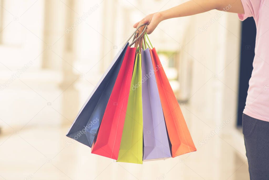 Female holding colorful shopping bags on blurry background