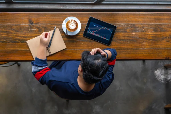 Asiatischer Wirtschaftsanalyst beobachtet Aktienhandel Graph auf Tablet — Stockfoto