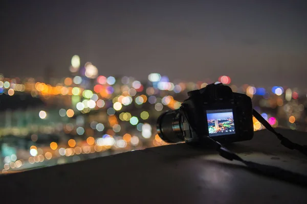 Camera put on rooftop edge with bokeh night city background — Stock Photo, Image