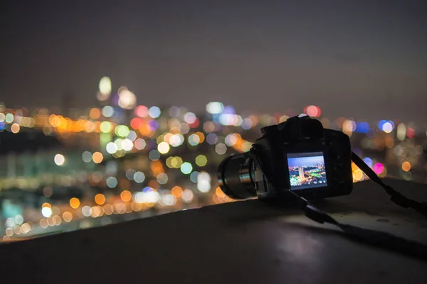 Cámara puesta en el borde de la azotea con fondo bokeh noche de la ciudad — Foto de Stock