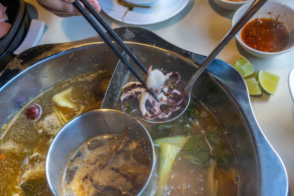 아시아 사람들은 젓가락을 사용하여 아시아 해산물 핫 팟을 먹는다 — 스톡 사진