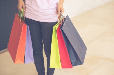 Kadın eli ağır ve renkli alışveriş torbaları taşıyor.