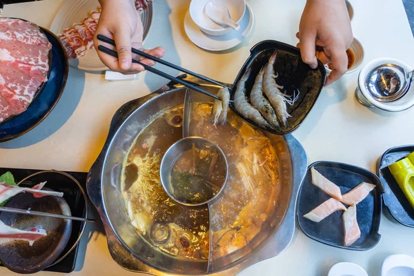 Vista de ángulo alto de la mano humana poniendo camarones en el hotpot — Foto de Stock