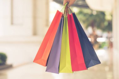 İnsan elinin renkli alışveriş torbalarıyla çekilmiş yakın bir fotoğrafı.