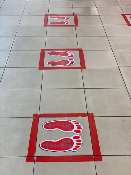 Red color footprint symbols on the floor for social distancing — Stok fotoğraf