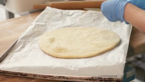 Massa de pizza deitada em papel na bandeja para assar no forno no café italiano de perto — Vídeo de Stock