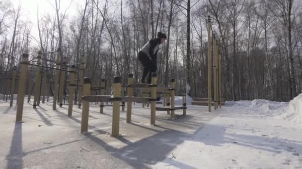 Sportler springt beim Wintercrossfit-Training auf Sportplatz auf Bank — Stockvideo