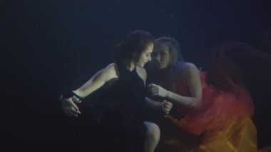 İki çekici kadın şifon elbise birlikte yüzme karanlık havuzunda sualtı
