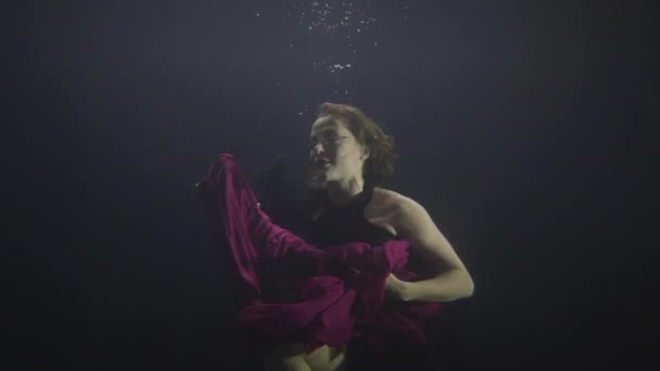 Mujer atractiva nadando bajo el agua sobre fondo oscuro — Vídeos de Stock