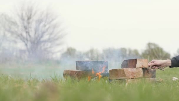 Męskie dłonie wypalania ognisko piknik podczas pieszej wycieczki na naturalne podłoże — Wideo stockowe
