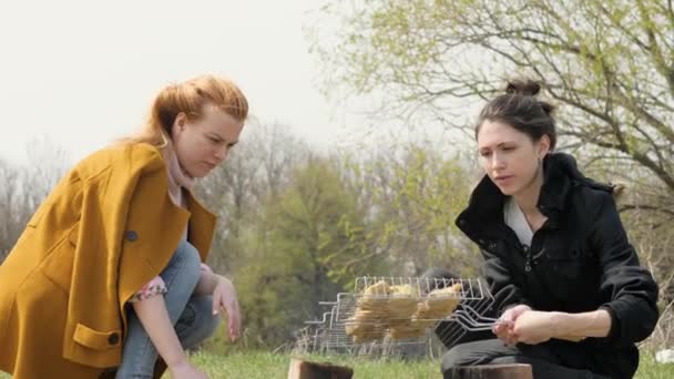 Duas mulheres durante o churrasco de carne cozinhando no fogo no piquenique na natureza — Vídeo de Stock