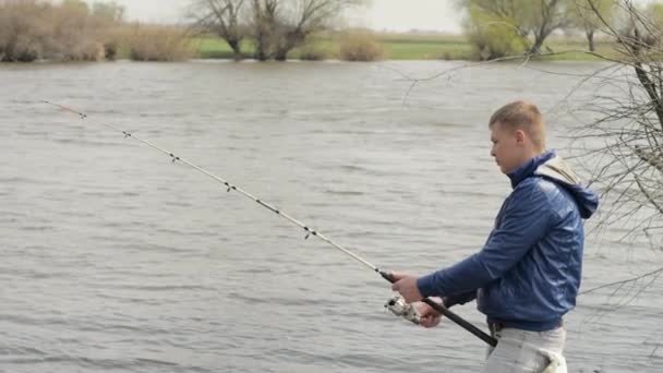 Rybář, chytání ryb a rybolov naviják na pozadí říční voda — Stock video