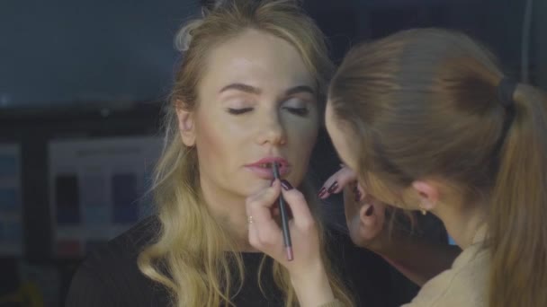 Makeup stylist using cosmetics pencil for lips make up in beauty studio — Stock Video