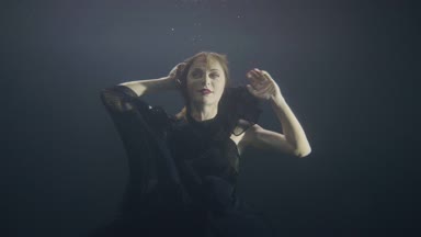 Siyah elbiseli karanlık havuzda su altında deniz kızı gibi yüzme gizemli kadın