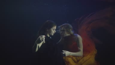 İki seksi kadın şifon elbise birlikte yüzme karanlık havuzunda sualtı