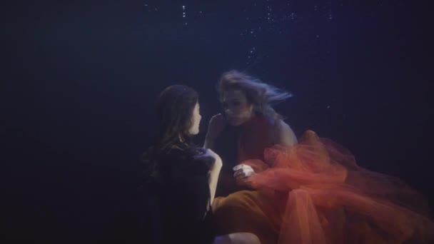 Paar lesbische Frau im Chiffonkleid schwimmt zusammen unter Wasser in dunklen Pool — Stockvideo