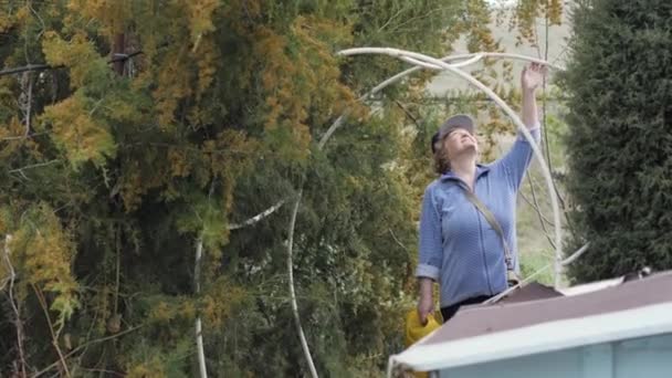 Mulher jardineiro segurando na mão pote de rega e andando no quintal do jardim — Vídeo de Stock