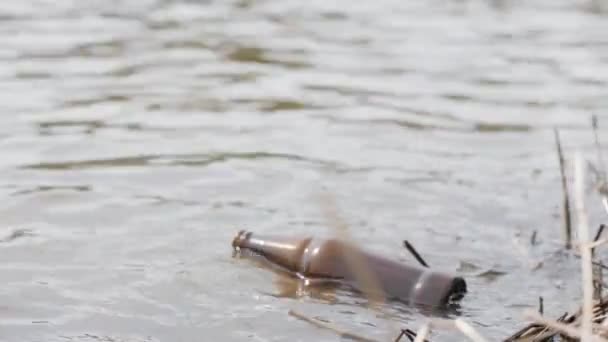 Botella de cerveza vacía flotando en el agua del río. Contaminación del agua y el medio ambiente — Vídeos de Stock