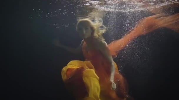 Mysteriöse Frau schwimmt wie eine Meerjungfrau unter Wasser vor dunklem Hintergrund — Stockvideo