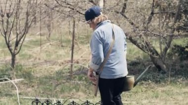 Dekoratif bush Bahçe arka bahçede sulama için sulama kullanan bahçıvan kadın olabilir