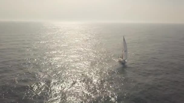 Yate de vela con en el mar azul y la luz del sol que refleja desde la vista aérea del agua — Vídeo de stock