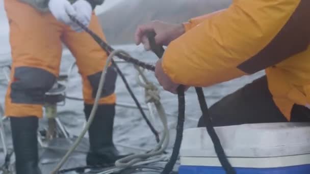 Два моряка работают и завязывают морские узлы на веревках на борту судна — стоковое видео