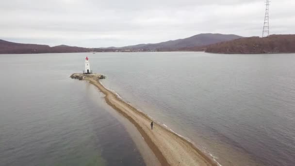 Faro vista aerea sulla riva del mare. Passeggiata turistica sul sentiero verso il faro del mare — Video Stock