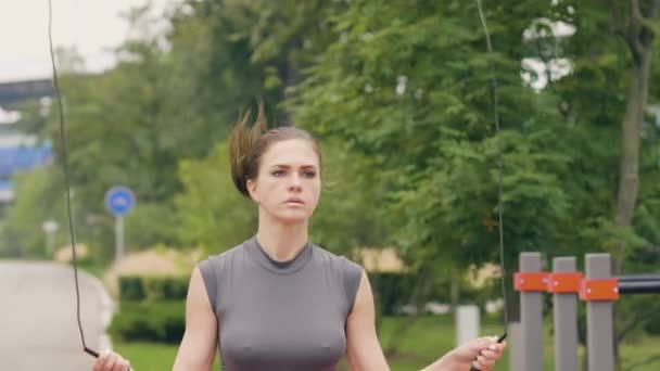 Atleta mujer usando saltar la cuerda para el entrenamiento al aire libre en el parque de verano — Vídeos de Stock