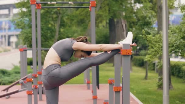 Ung kvinna gör stretching övningar på konditionsträning i sommaren park — Stockvideo