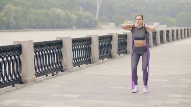 Hermosa mujer haciendo ejercicio en cuclillas con expansor deportivo en el entrenamiento crossfit — Vídeos de Stock