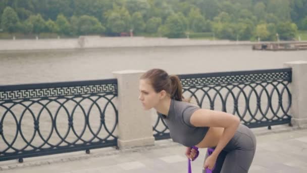 Красива жінка тренування вправи зі спортивним екстрадитором в літньому парку — стокове відео