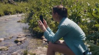 Nehir kıyısında dinlenme ve fotoğraf cep telefonuyla yapıyor turist kadın