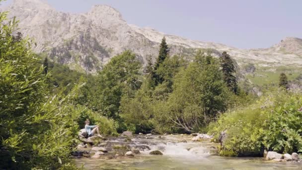 Kadın dağ panorama akışıyla hızlı nehir kıyısında. Dağ manzarası — Stok video