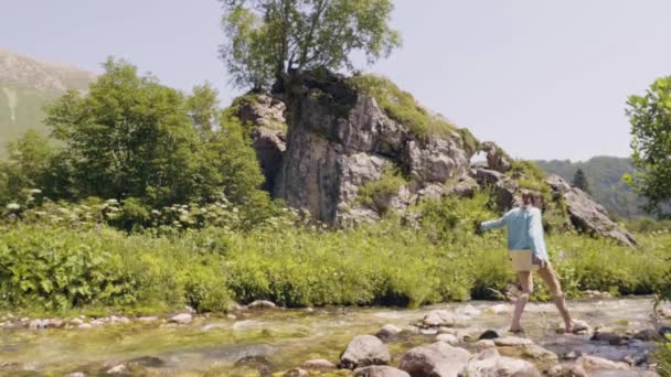 Kadın taş'a nehir çapraz. Turist kadın adım akan nehir içinde taşlar üzerinde — Stok video