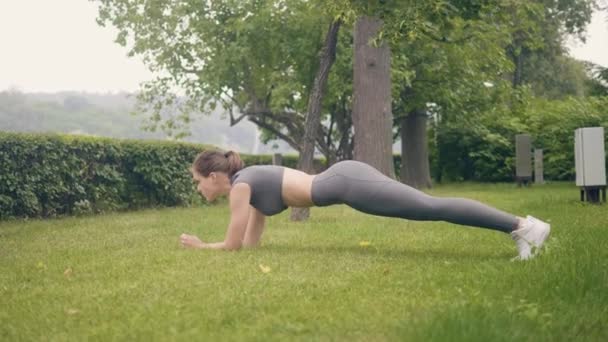 Fitness vrouw opleiding plank oefening op gras in de zomer park — Stockvideo